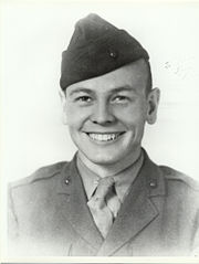  A young man dressed in his military uniform and wearing a Marine Corps style hat. He is smiling.